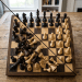 Chess board with black pieces arranged and white pieces scattered randomly